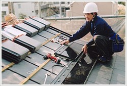 屋根の上で施工作業をする職人